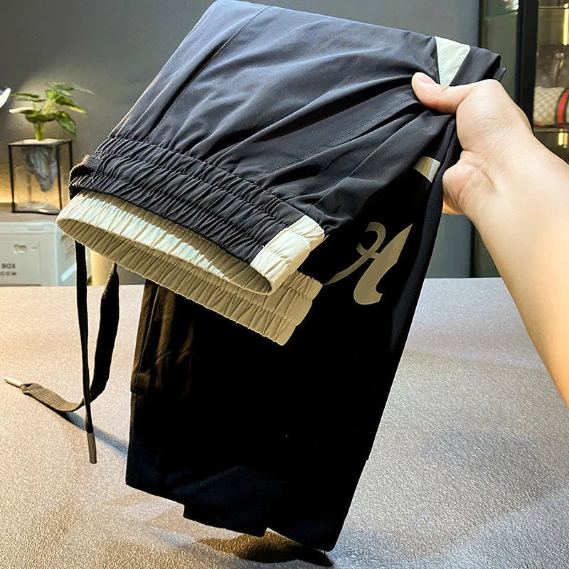 Men's solid black cropped trousers with banded ankle cuffs made from thin ice silk cotton fabric.