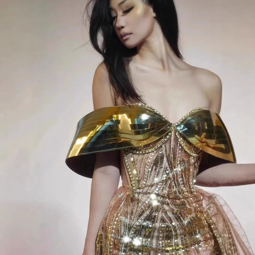 Gold sequinned strapless long evening dress with a high thigh split on a model.