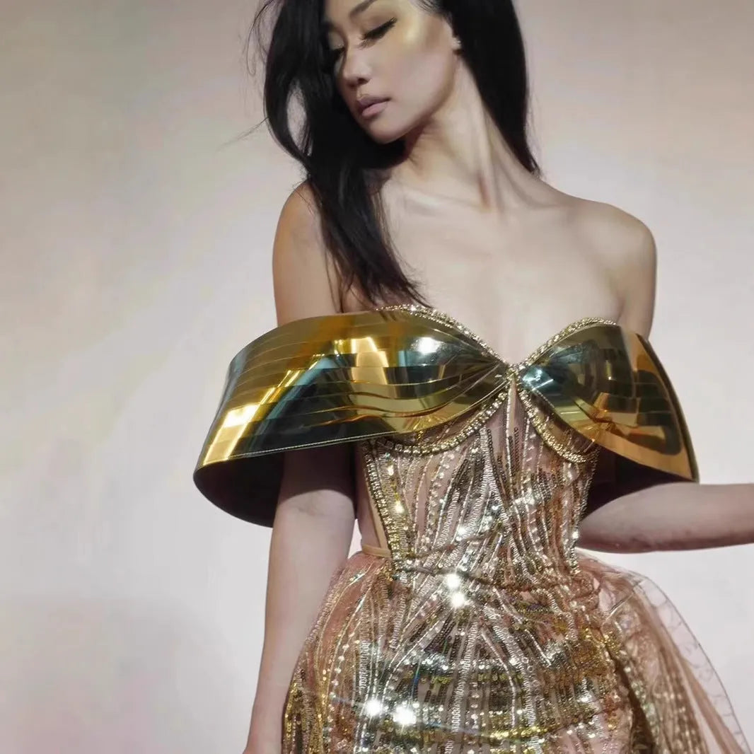 Gold sequinned strapless long evening dress with a high thigh split on a model.