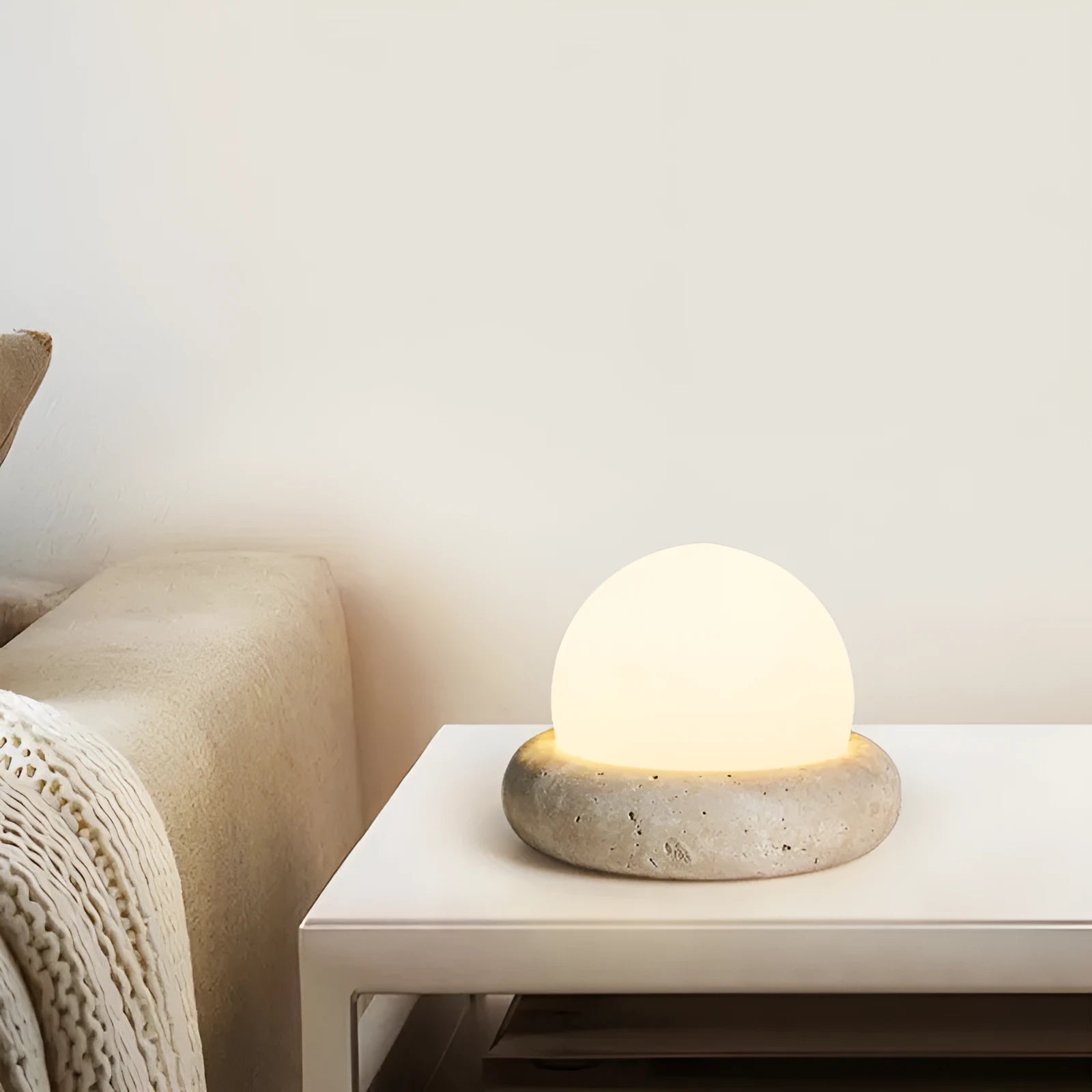 Modern cream-coloured bedside table lamp with wireless remote control on a nightstand.