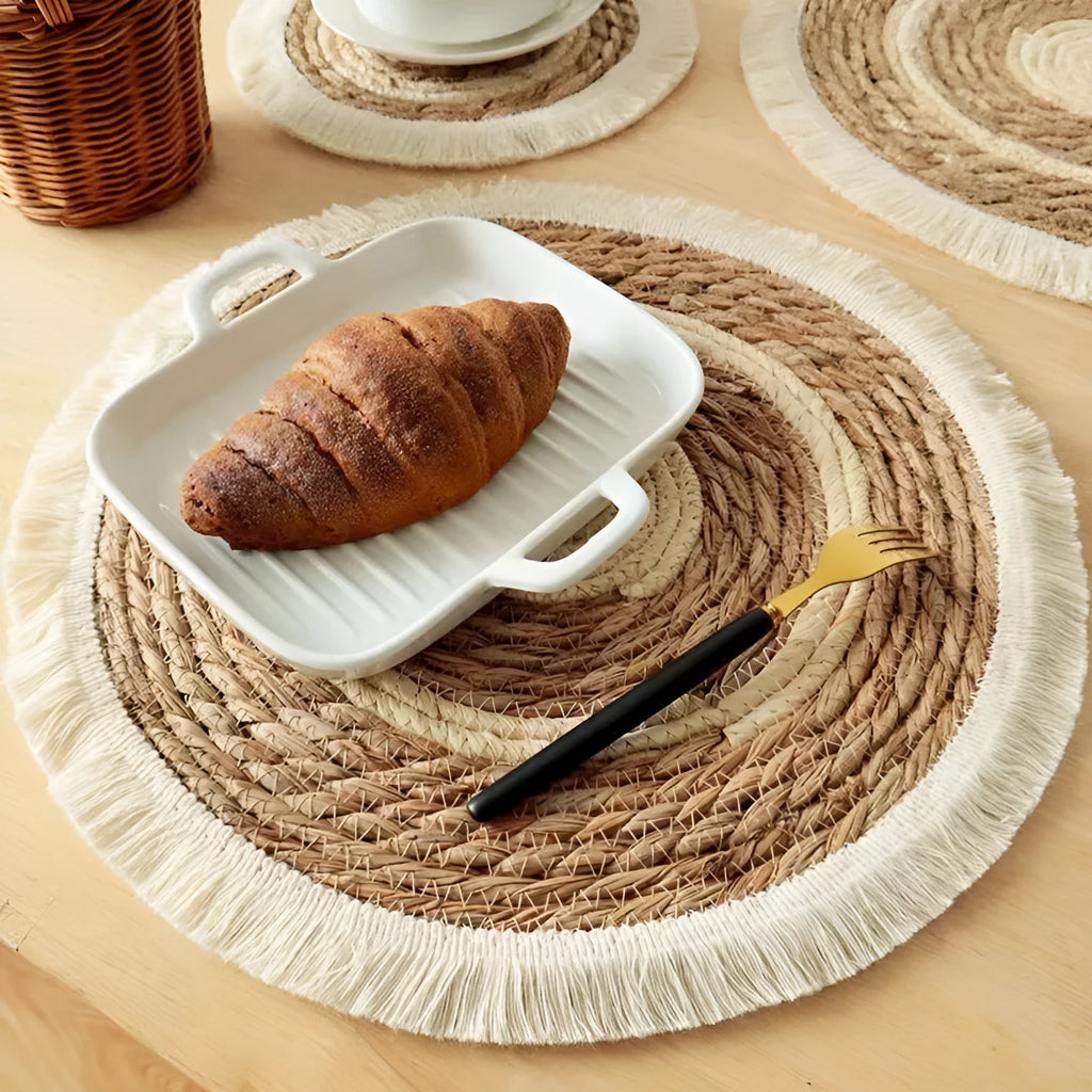 Round papyrus straw placemat with tassel edge in neutral colour on dining table