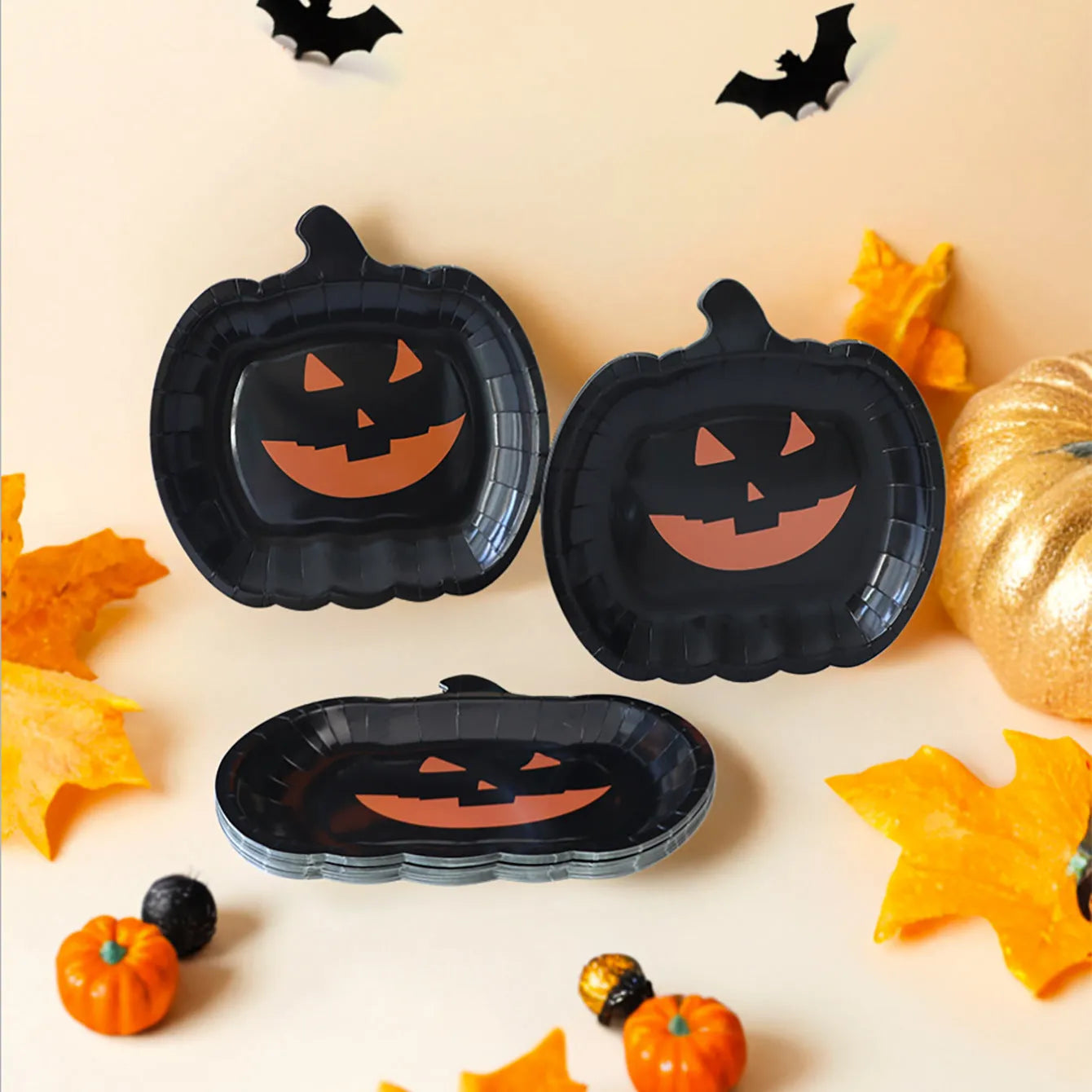 A pack of black disposable paper plates with a pumpkin design for Halloween, shown in 9-inch size.