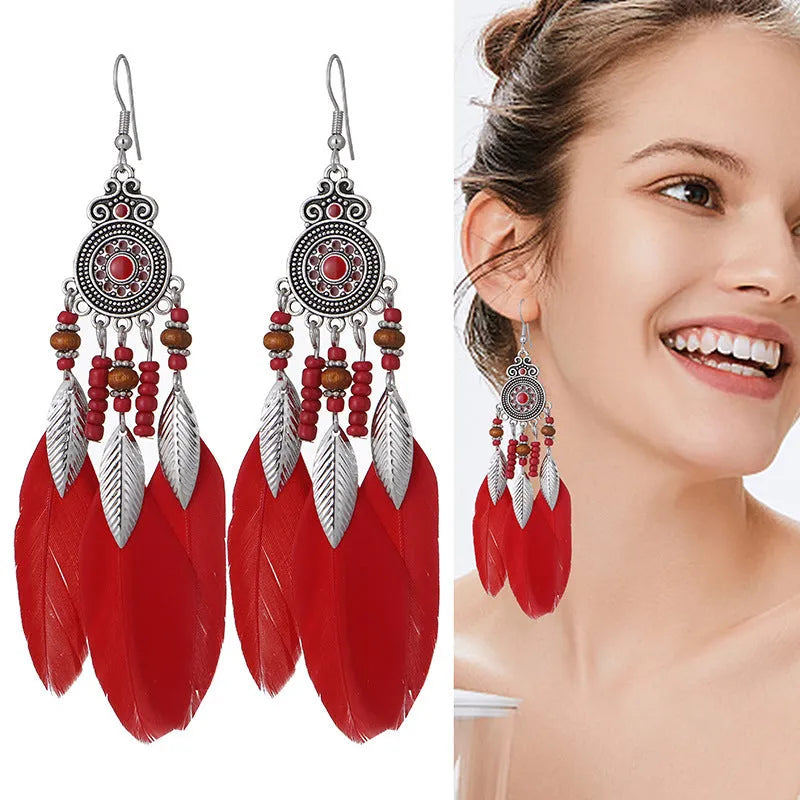 Close-up of a pair of bohemian-style feather-shaped earrings with a leaf pattern, in an alloy electroplated finish.