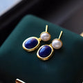 A pair of simple stud earrings featuring a deep blue lapis lazuli pearl set in 925 silver.