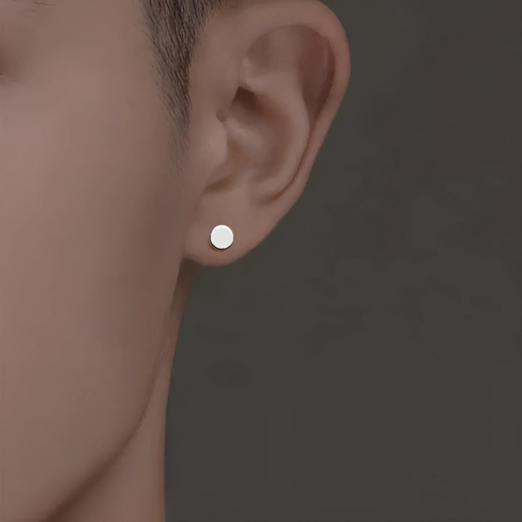 A pair of simple round sterling silver S999 stud earrings on a flat surface, shown in silver and black finishes.