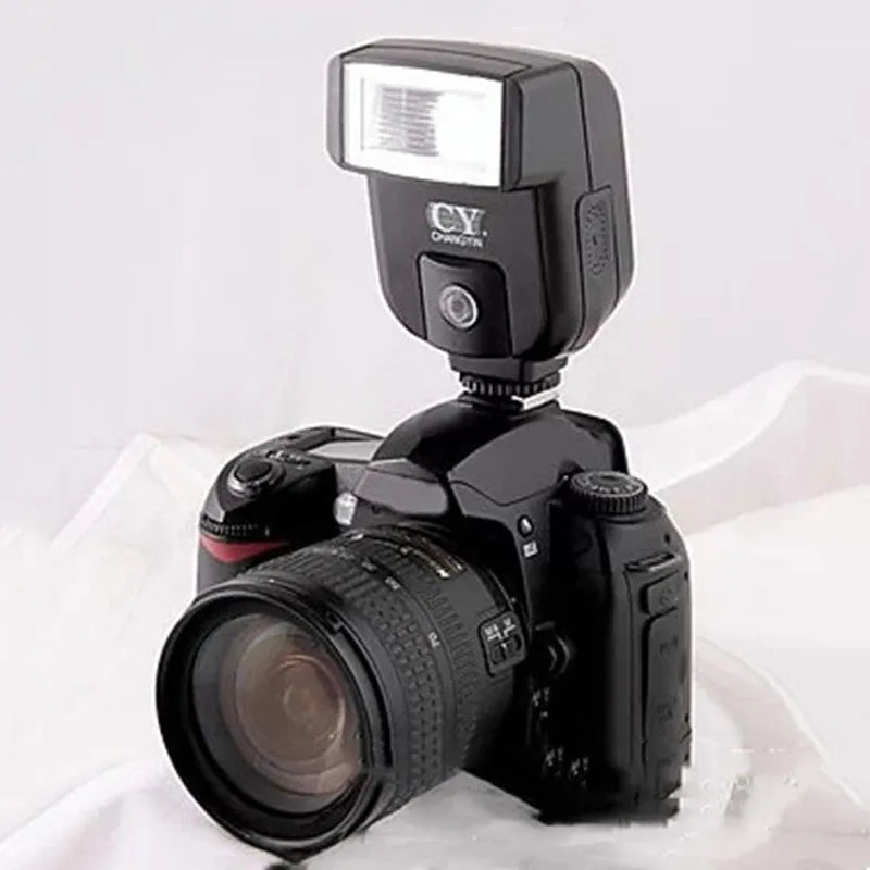 Compact black SLR camera flash with tilted head mounted on a DSLR camera hot shoe.