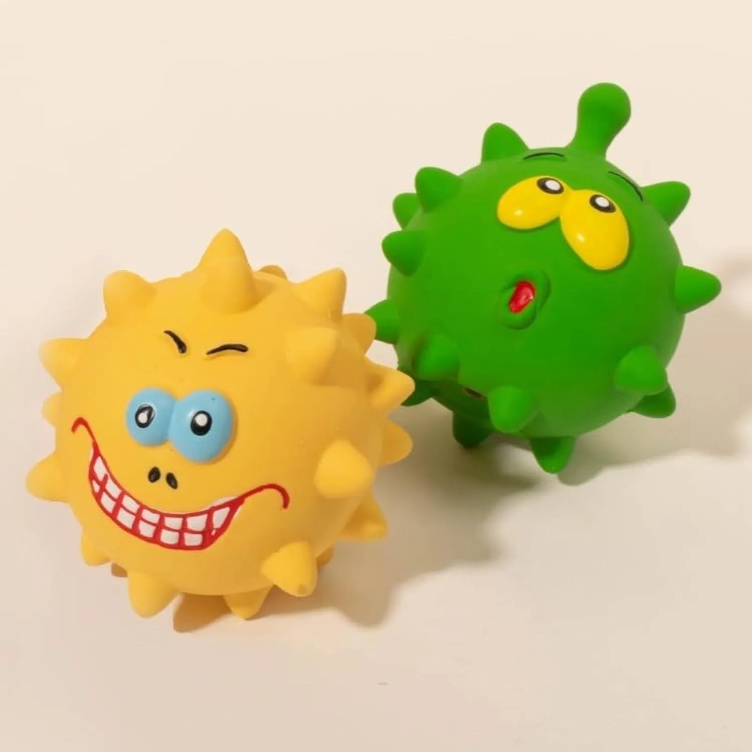 Four coloured natural latex squeaky dog balls with cute faces measuring 7.5cm