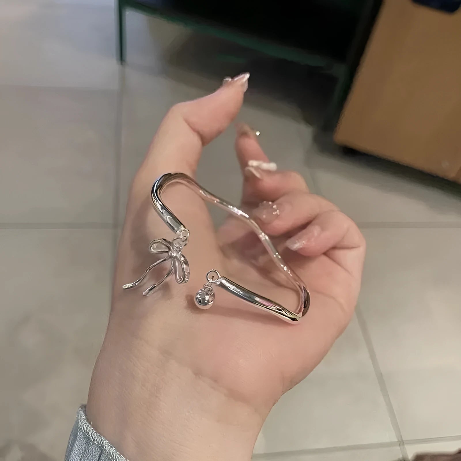 Silver adjustable women's bracelet with bow-shaped bell opening closure on zinc alloy chain