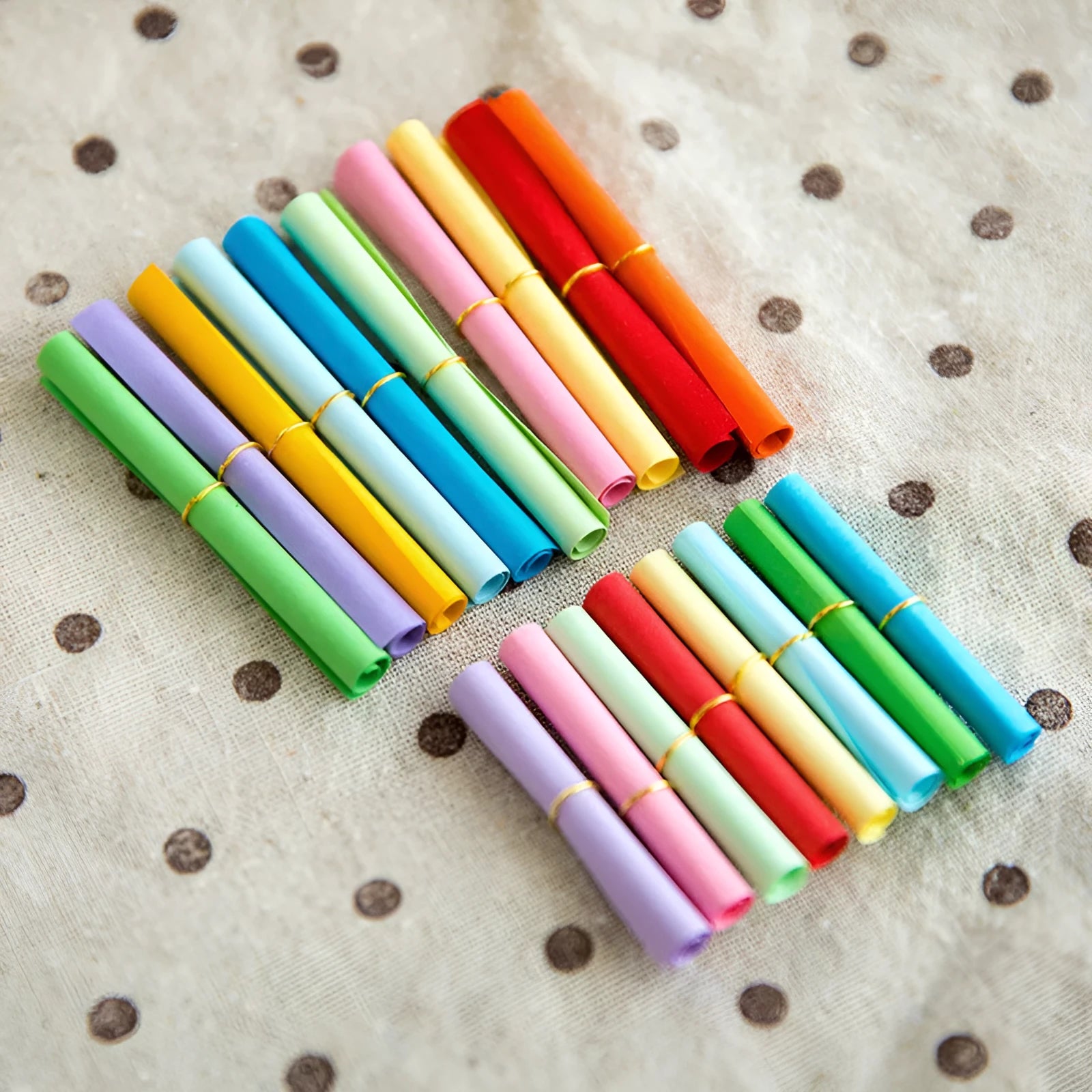 Assorted colourful mini paper scrolls with central metal eyelets for drift bottle messages.
