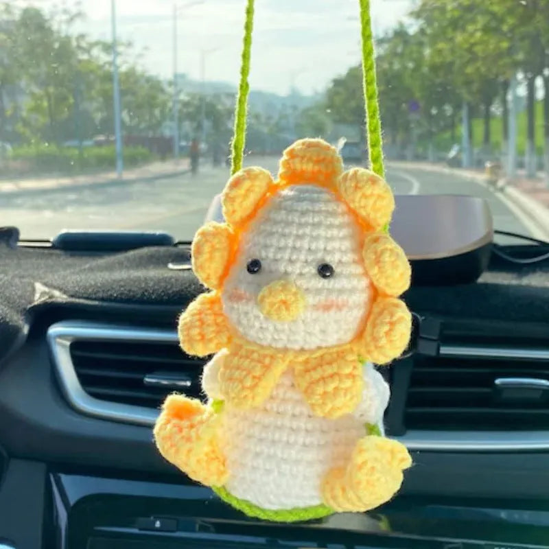 Green and white knitted car plant decoration with hanging rope on car dashboard