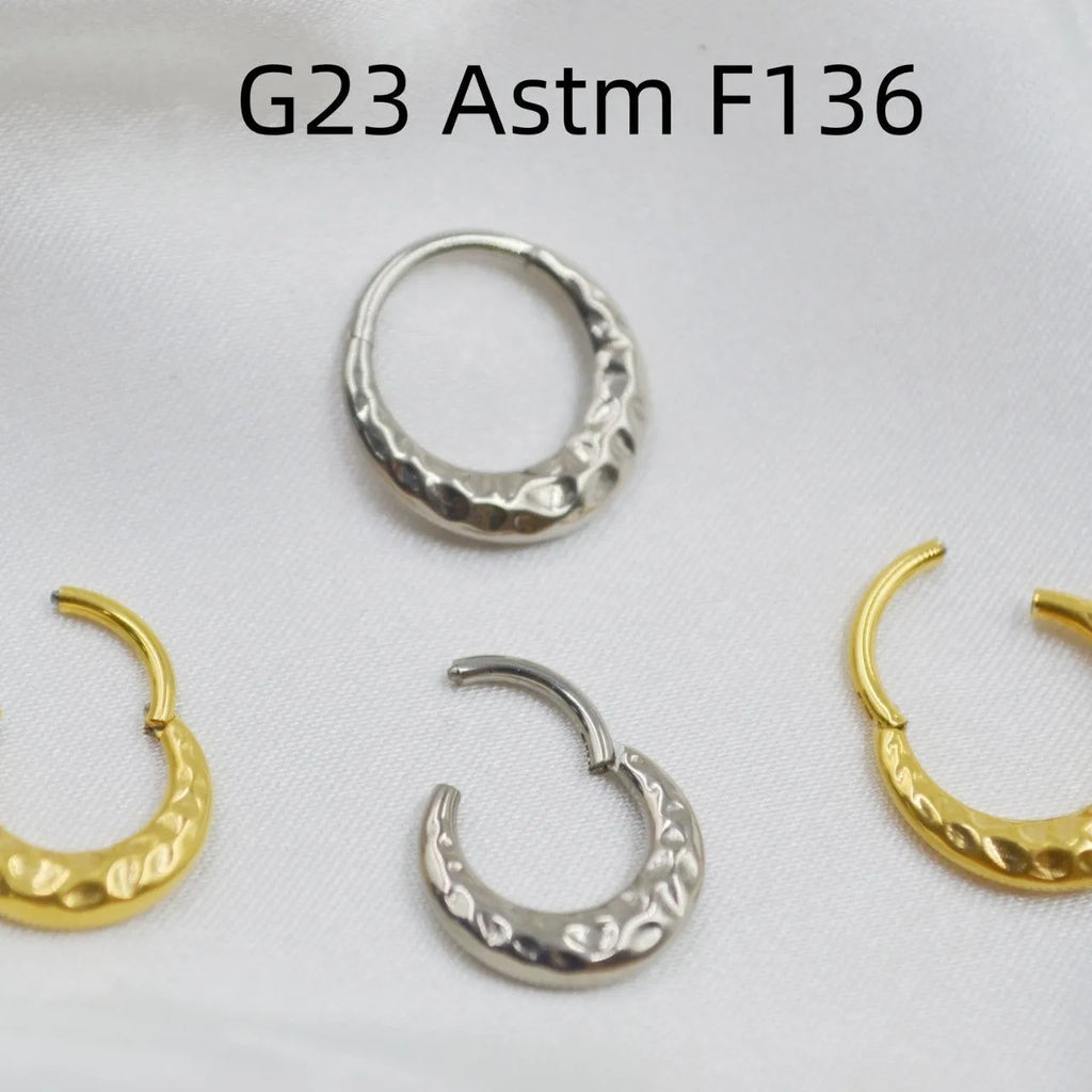 Close-up of a titanium alloy nose ring with concave-convex texture in a gold anodised finish.