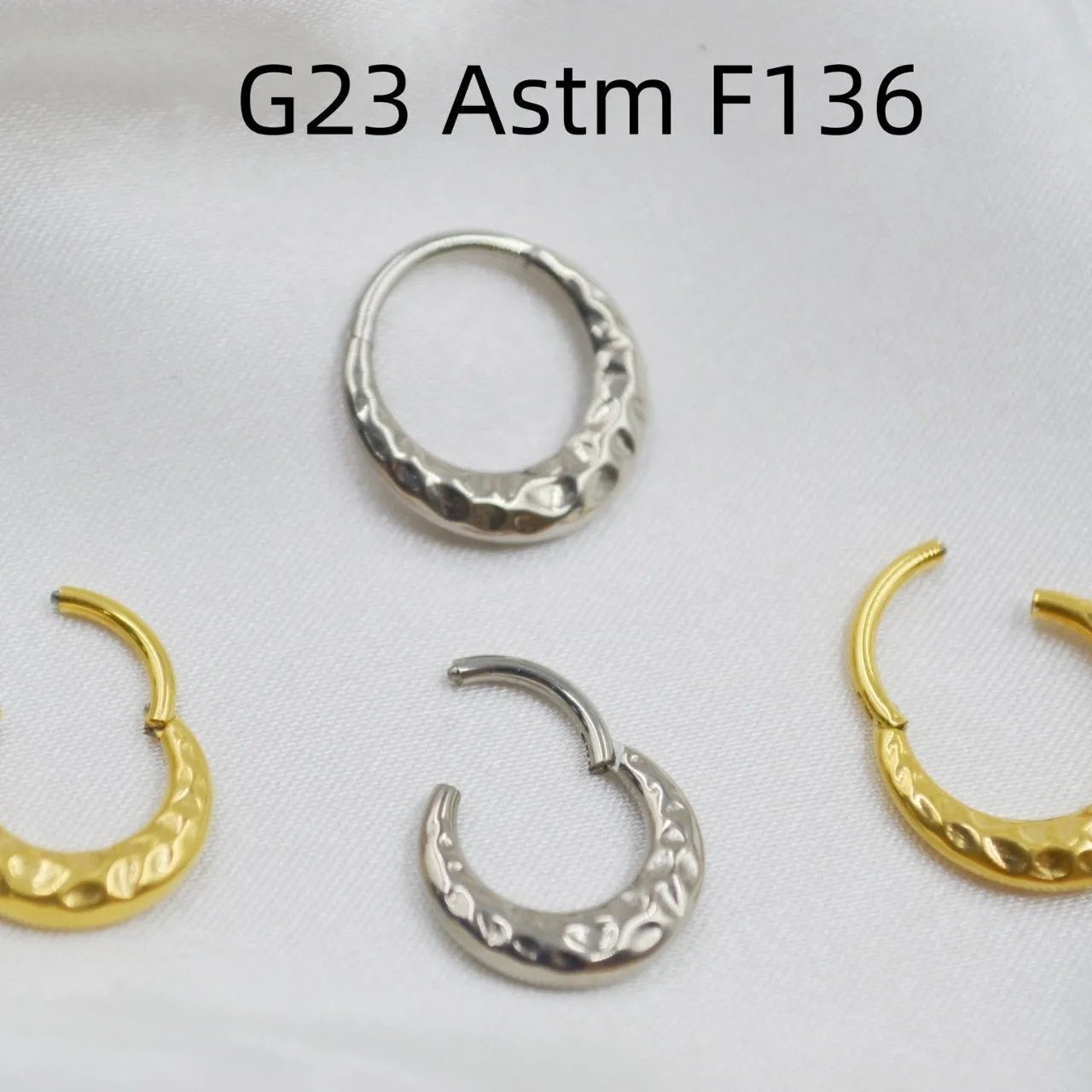 Close-up of a titanium alloy nose ring with concave-convex texture in a gold anodised finish.