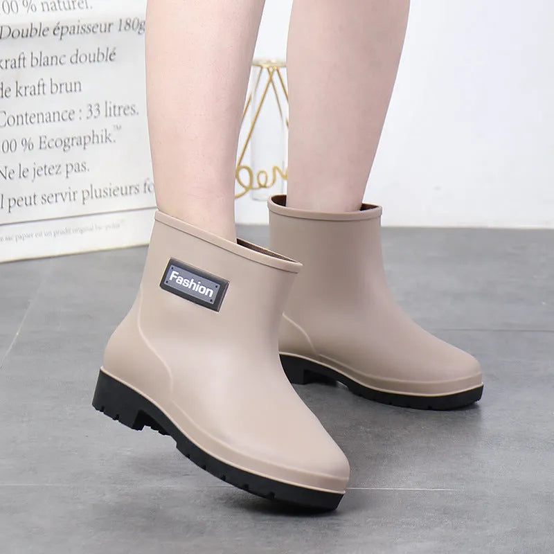 Women's black PVC mid-calf rain boot with low heel on a wet surface
