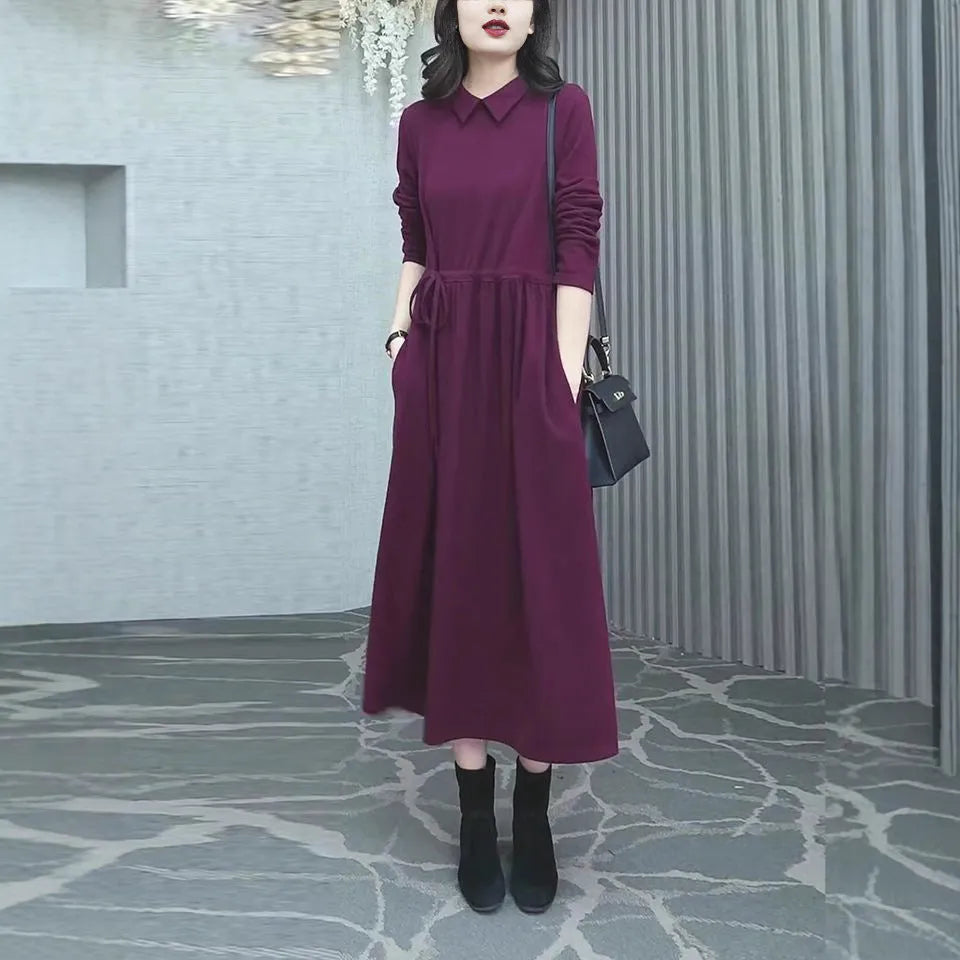 A purplish red plus size long sleeve dress with a long skirt, shown on a model.