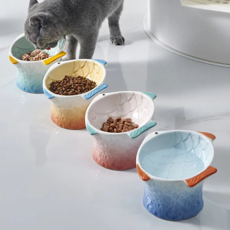 Blue fish-shaped ceramic cat bowl with tilted angle and elevated sides on a white background.
