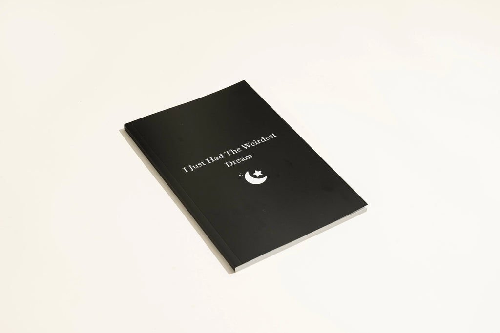 Black hardcover A5 dream journal notebook with plain paper pages open
