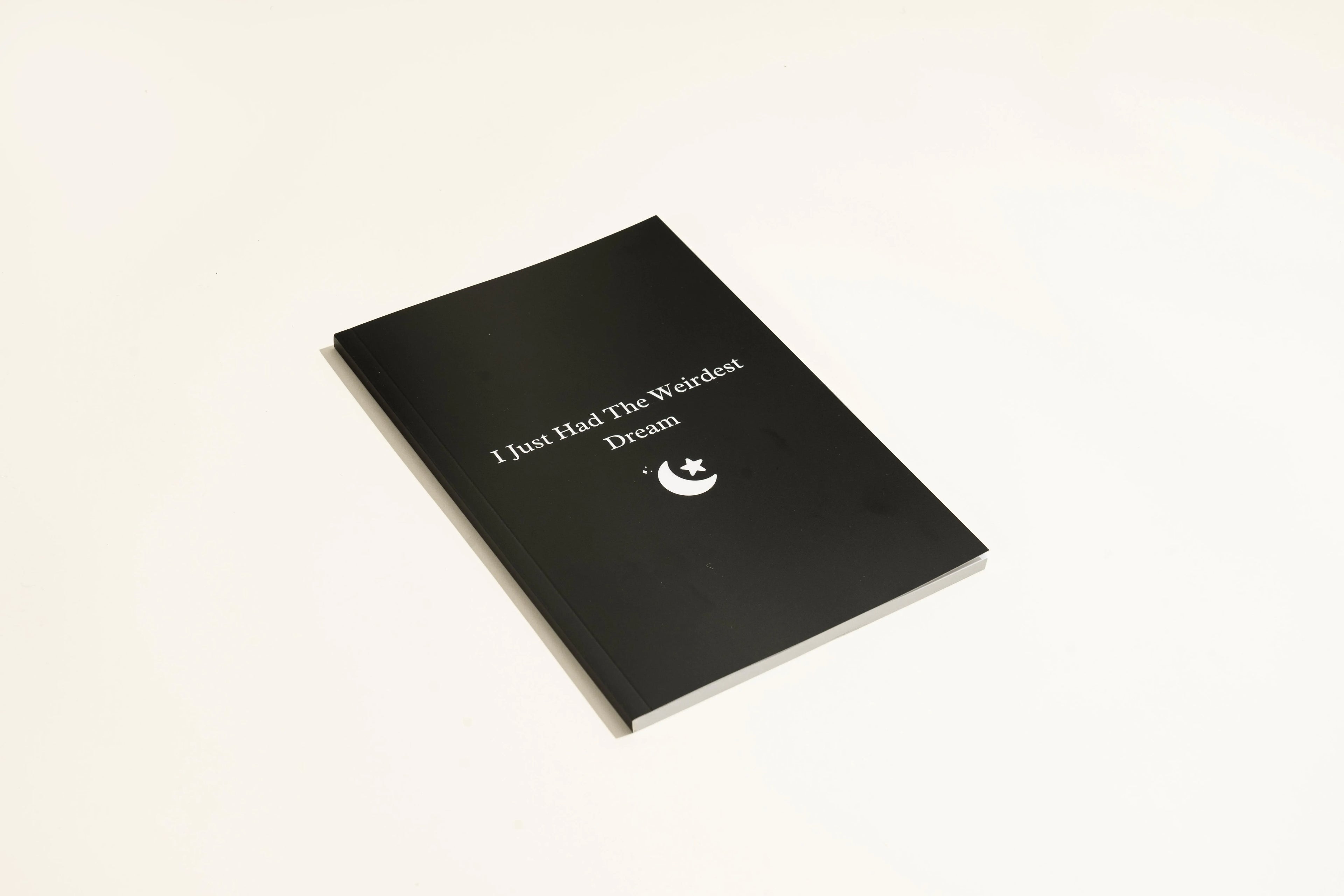 Black hardcover A5 dream journal notebook with plain paper pages open