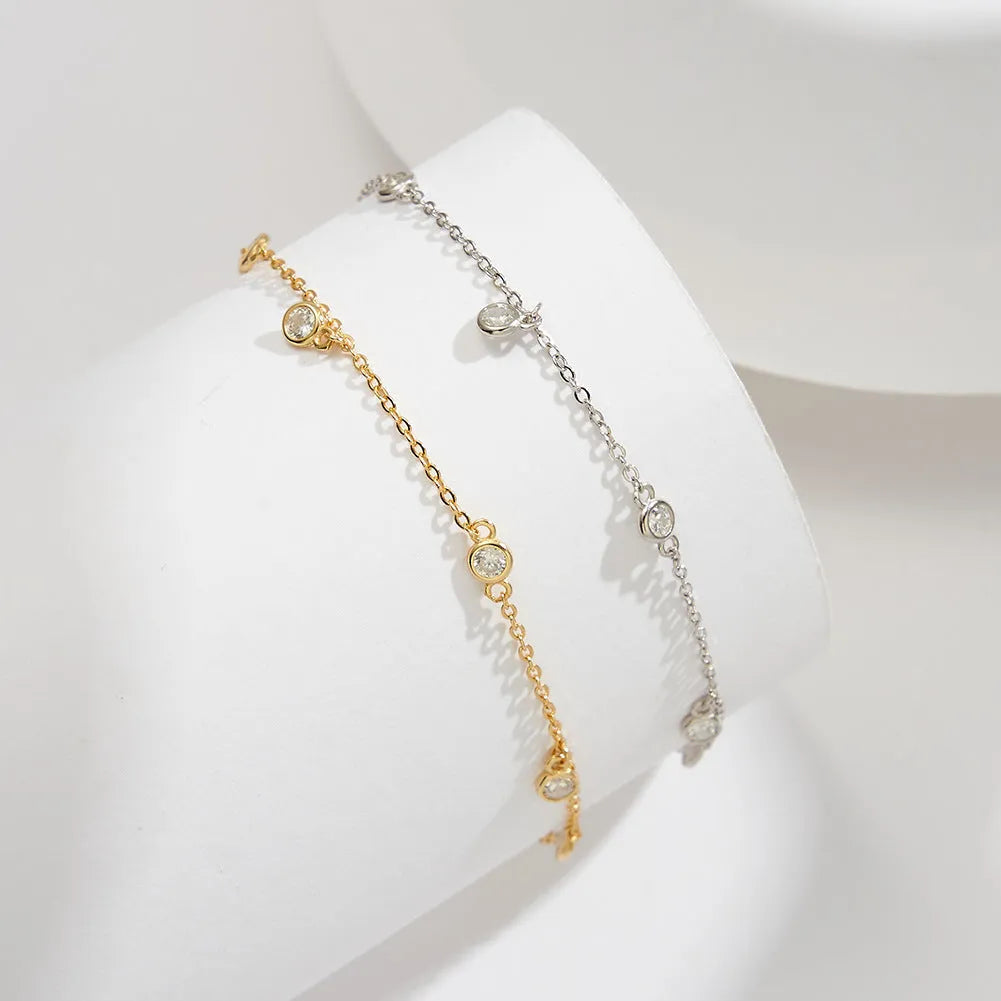 Women's sterling silver geometric zirconium pendant anklet on ankle, showing gold and white gold colour options.