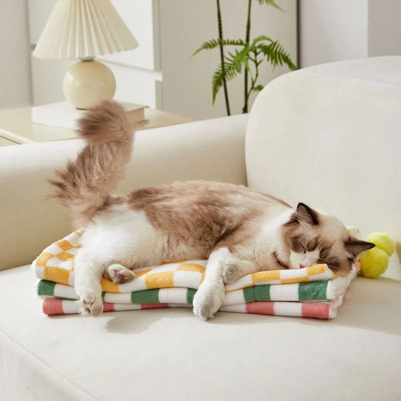 Green plaid pattern pet blanket with fur ball decoration on sofa