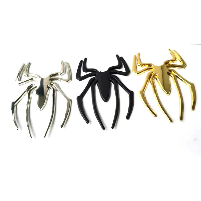 Three-dimensional zinc alloy spider bumper sticker in metallic colours on a surface.
