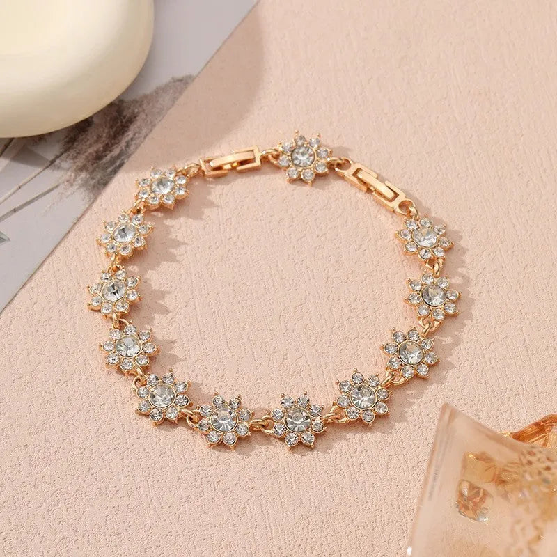 Gold tone flower-shaped bracelet with blue crystal gems on a wrist.