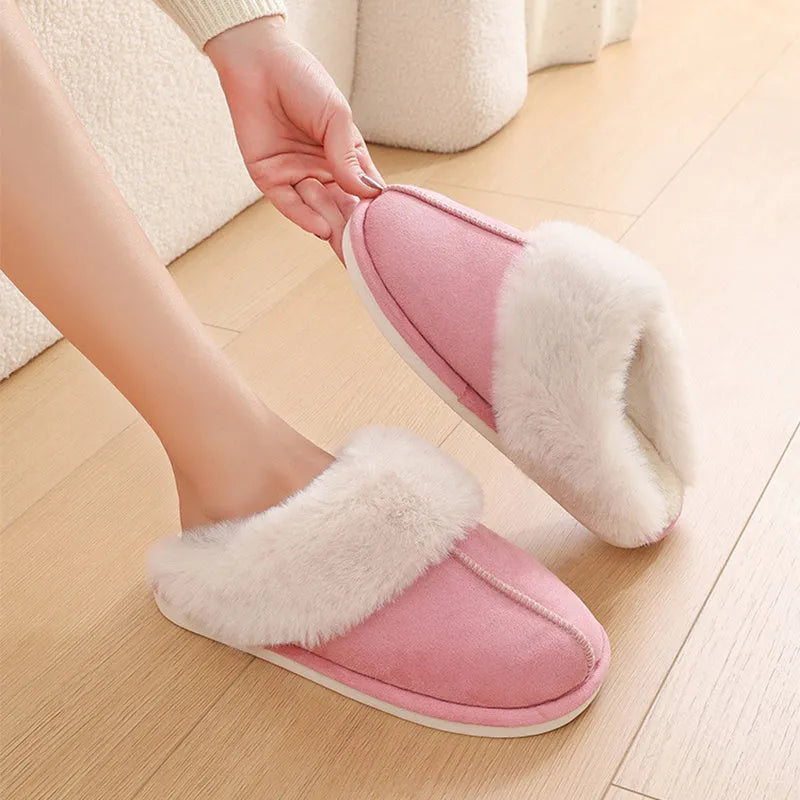 A pair of plush fur-lined indoor slippers with a round toe and a flat PVC sole.