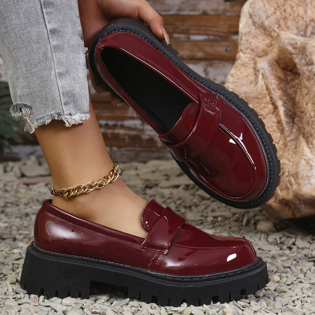 Women's black chunky heel slip-on loafers with a platform sole, shown on a foot.