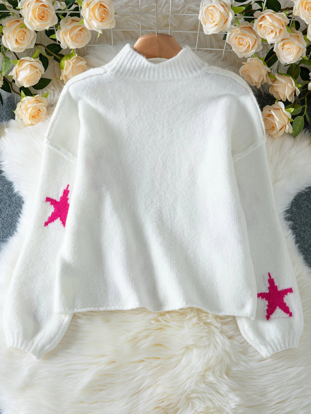 White women's loose turtleneck pullover sweater with a black five-pointed star pattern on the front.
