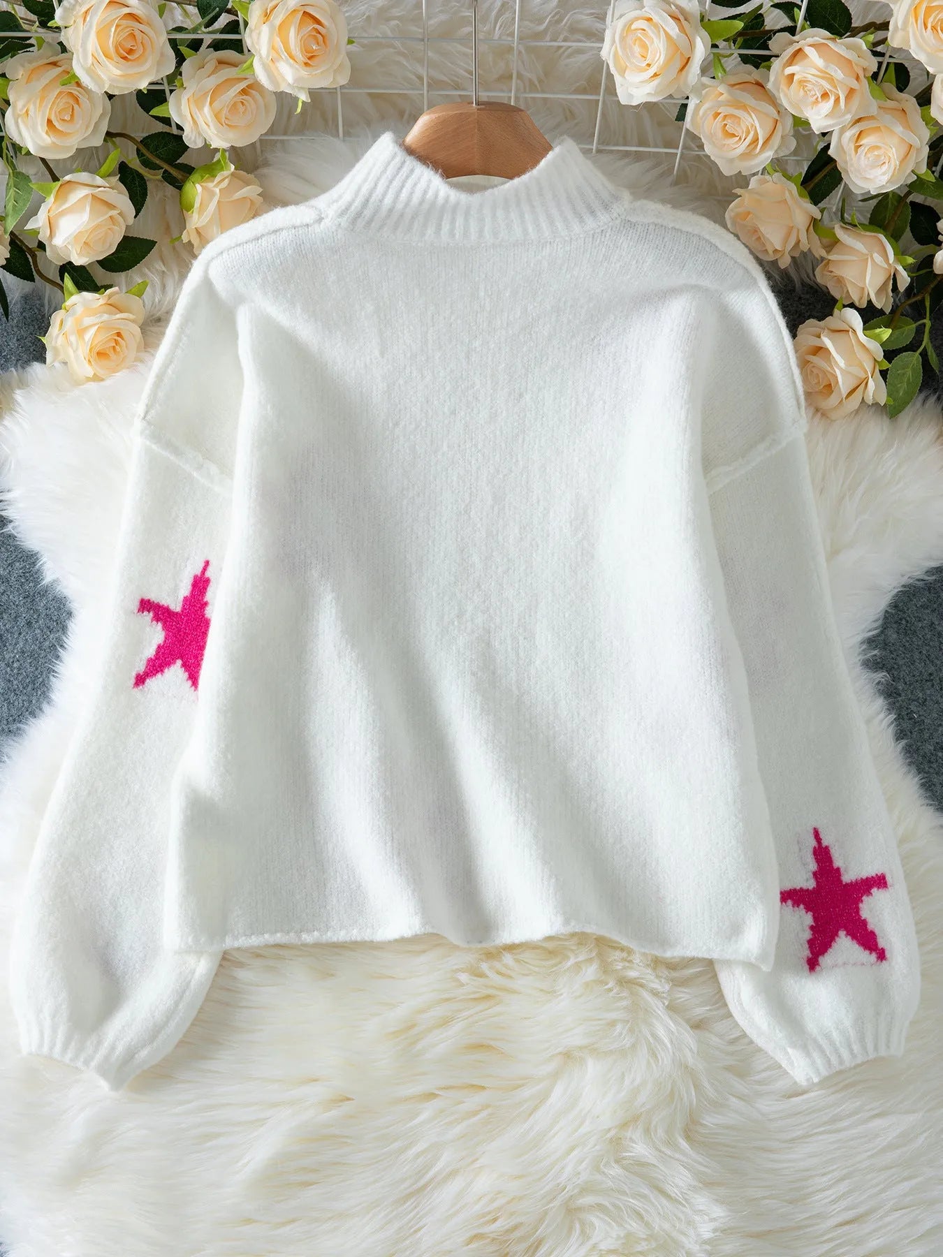 White women's loose turtleneck pullover sweater with a black five-pointed star pattern on the front.