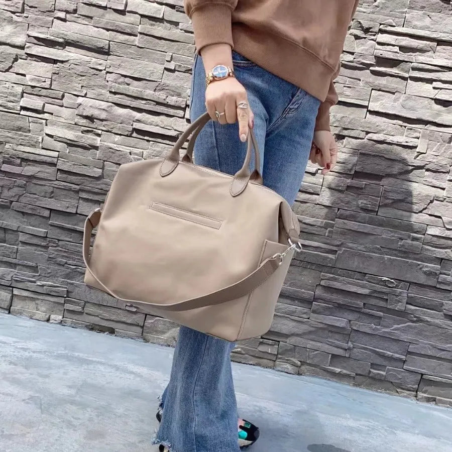 Black nylon waterproof shoulder bag with leather handles showing its large size