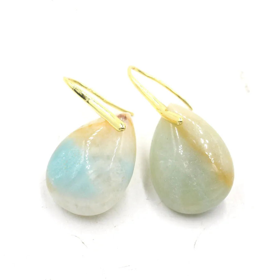 A pair of geometric water drop earrings in crystal, shown in an amethyst colour variant with an electroplated metal setting.