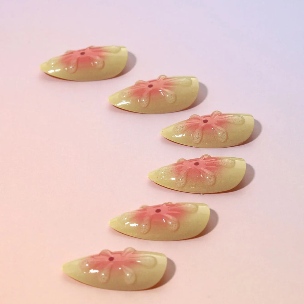 Set of pink plastic fake nails with raised 3D cartoon flower designs, jelly glue, and a nail file.