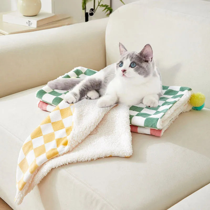 Green plaid pattern pet blanket with fur ball decoration on sofa