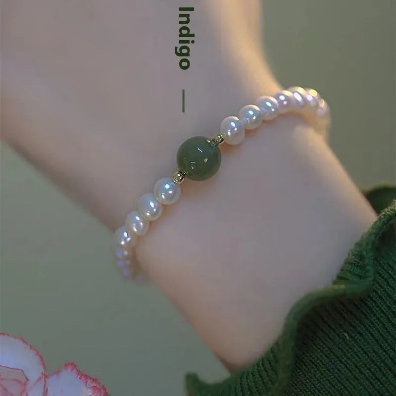 A Chinese style glass bracelet with bamboo leaf and bead designs on a wrist.