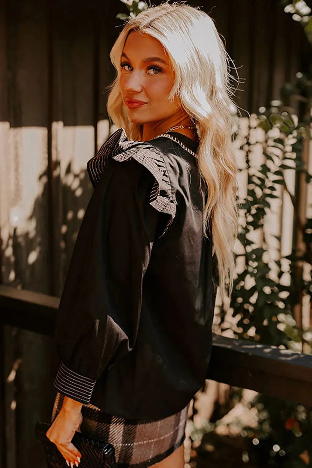 Black long sleeve blouse with V-neck and ruffle detailing on the sleeves.