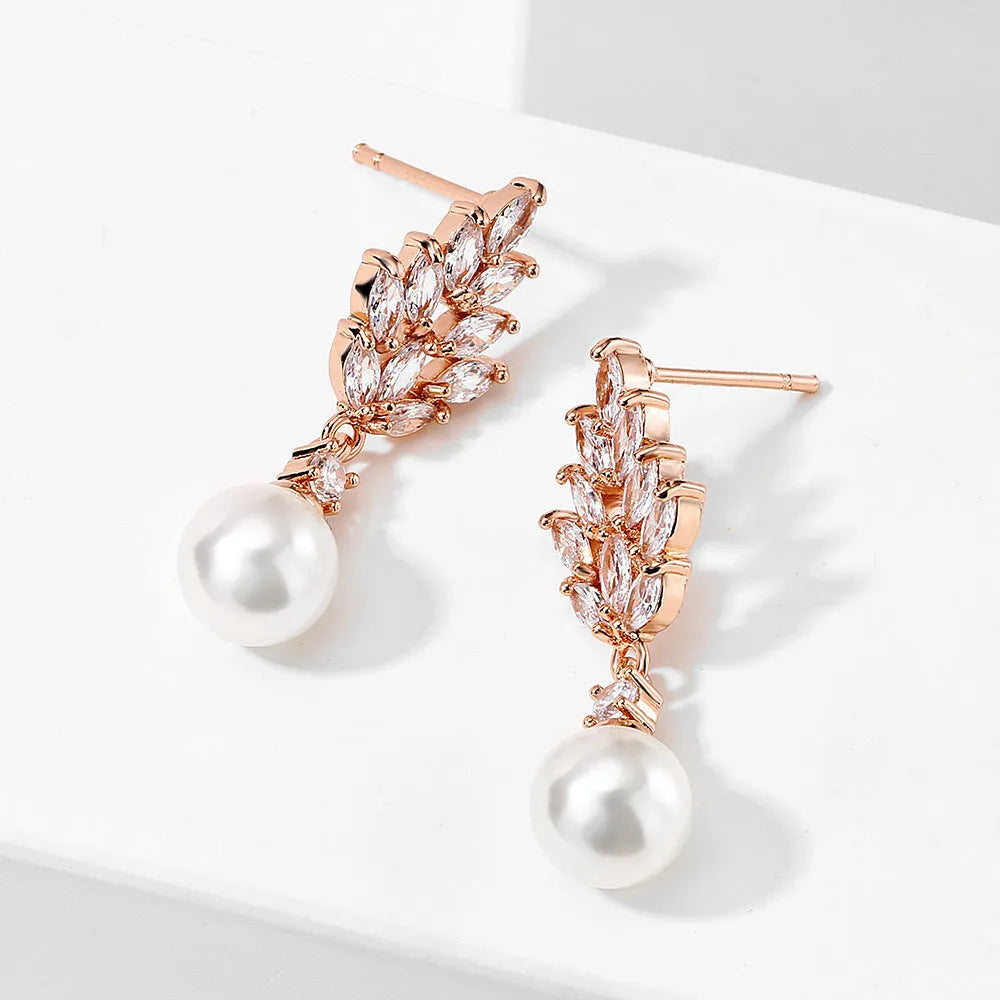 Geometric flower shaped earrings with micro inlaid zircon stones and pearl accents on a gold plated background.
