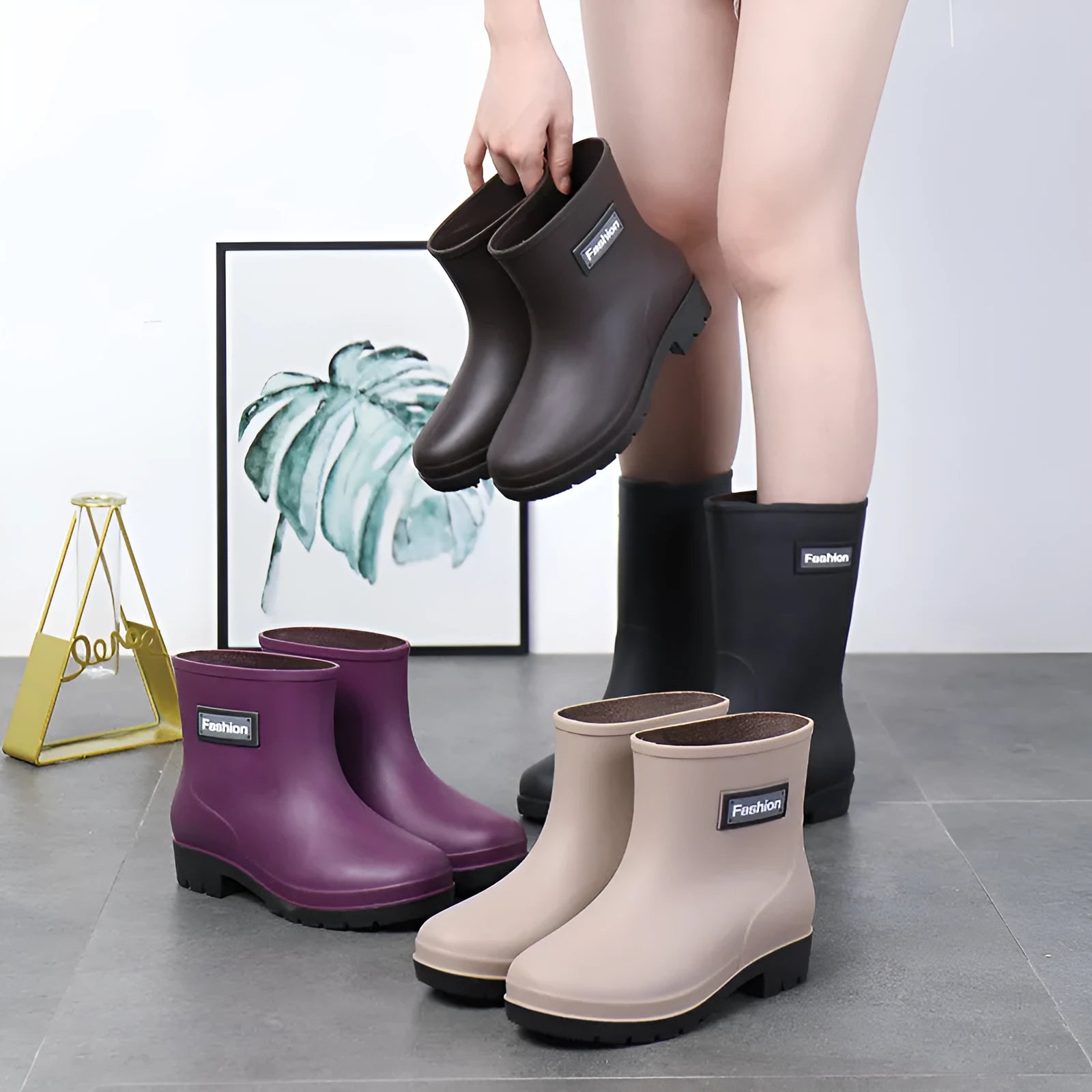 Women's black PVC mid-calf rain boot with low heel on a wet surface