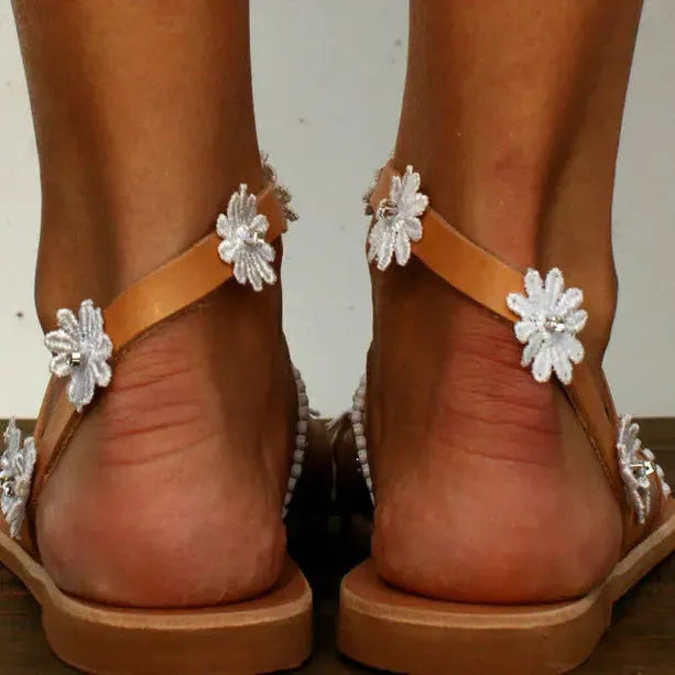 Brown Roman sandals with floral pattern, flat rubber sole, and herringbone toe design