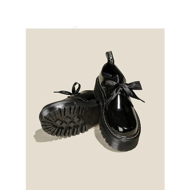 Women's black leather shoes with thick soles, cross straps featuring ribbon details, and lace-up closure