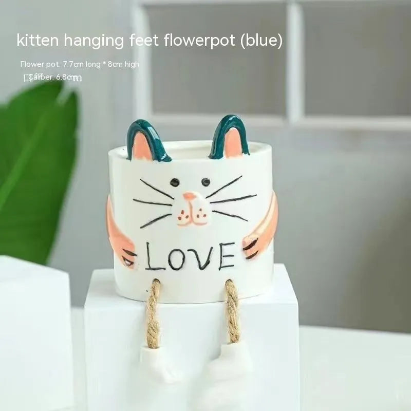 Ceramic cartoon-style succulent flowerpot with hanging foot design on desktop