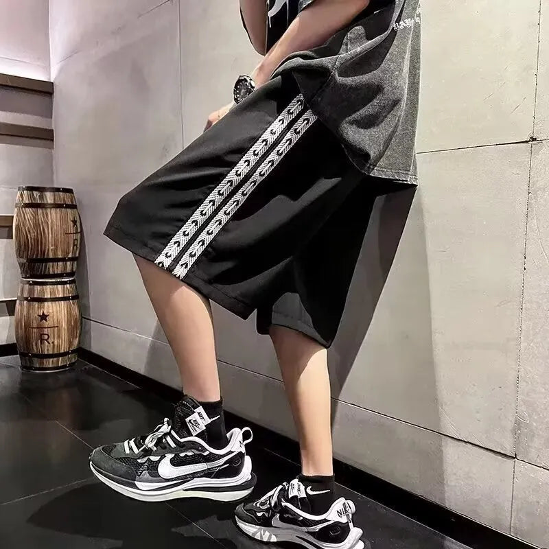Men's loose-fitting black baggy track pants with a sports style on a plain background.