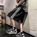 Men's loose-fitting black baggy track pants with a sports style on a plain background.