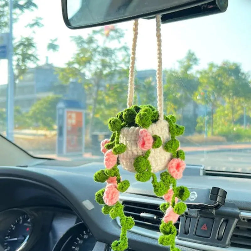 Green and white knitted car plant decoration with hanging rope on car dashboard