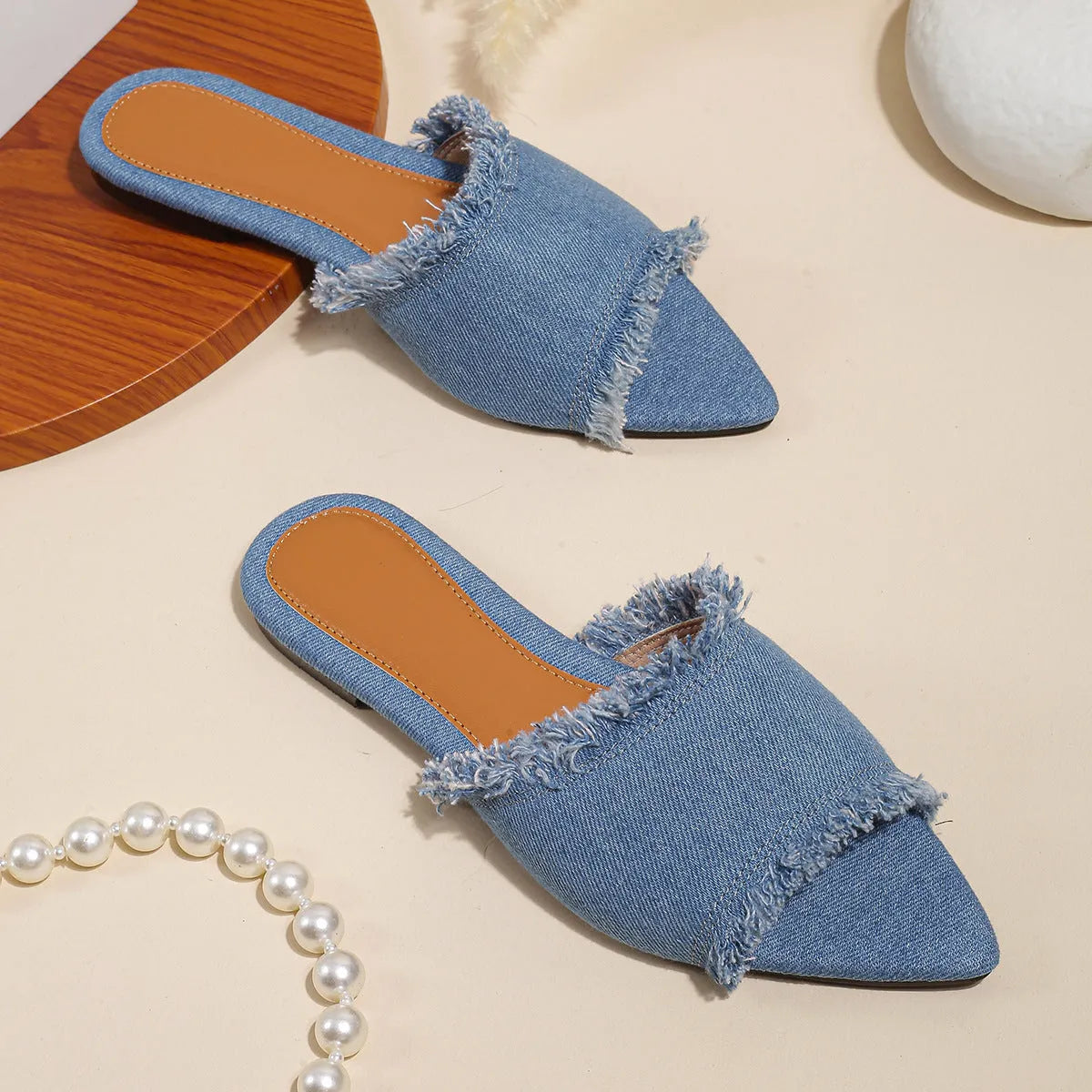 Women's denim flat slippers with a tassel detail and leather lining, shown in apricot colour.