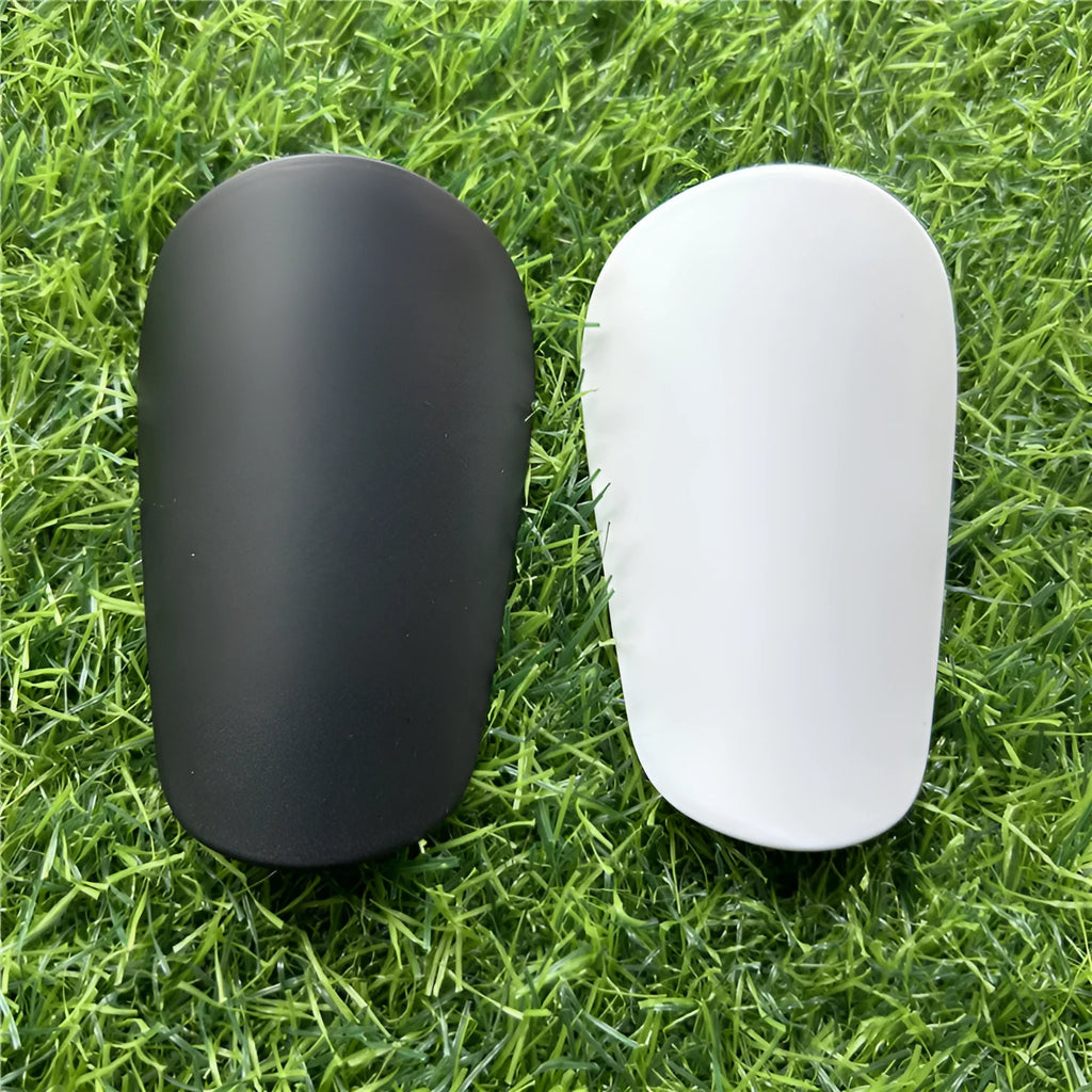 Extra small black and white plastic football shin guards for junior players, size 8cm by 5cm.