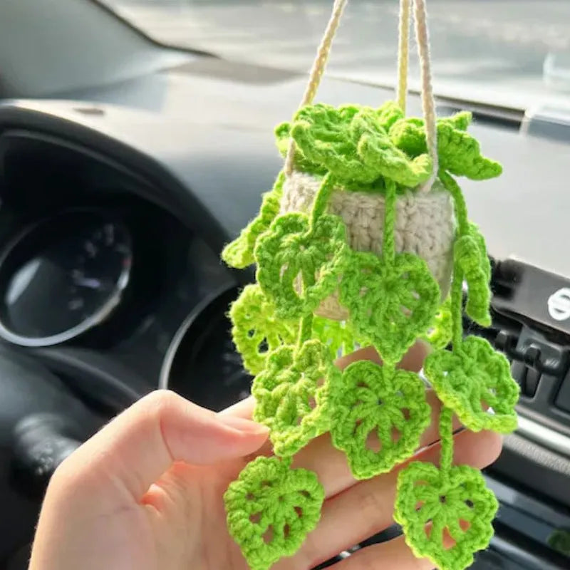 Green and white knitted car plant decoration with hanging rope on car dashboard