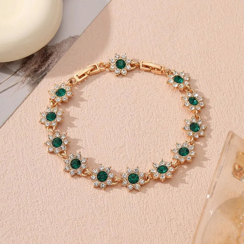 Gold tone flower-shaped bracelet with blue crystal gems on a wrist.