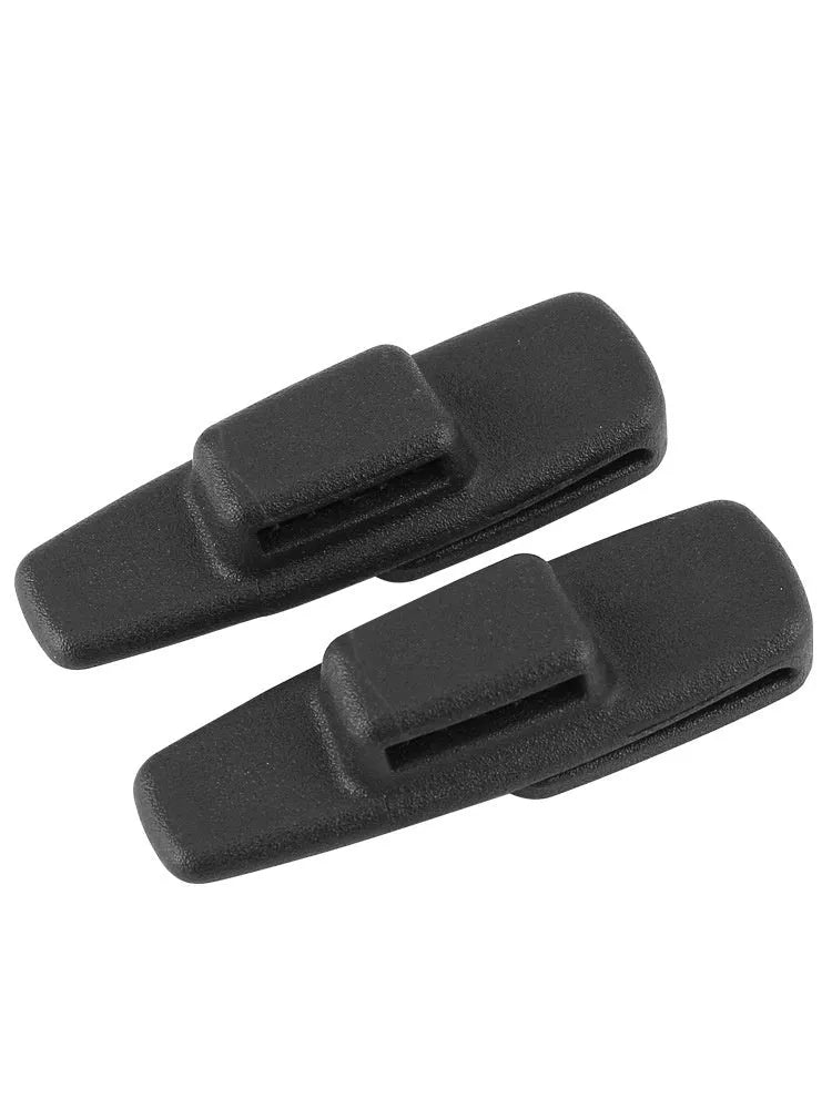 A pair of black plastic universal seat belt stopper clips on a car seat.
