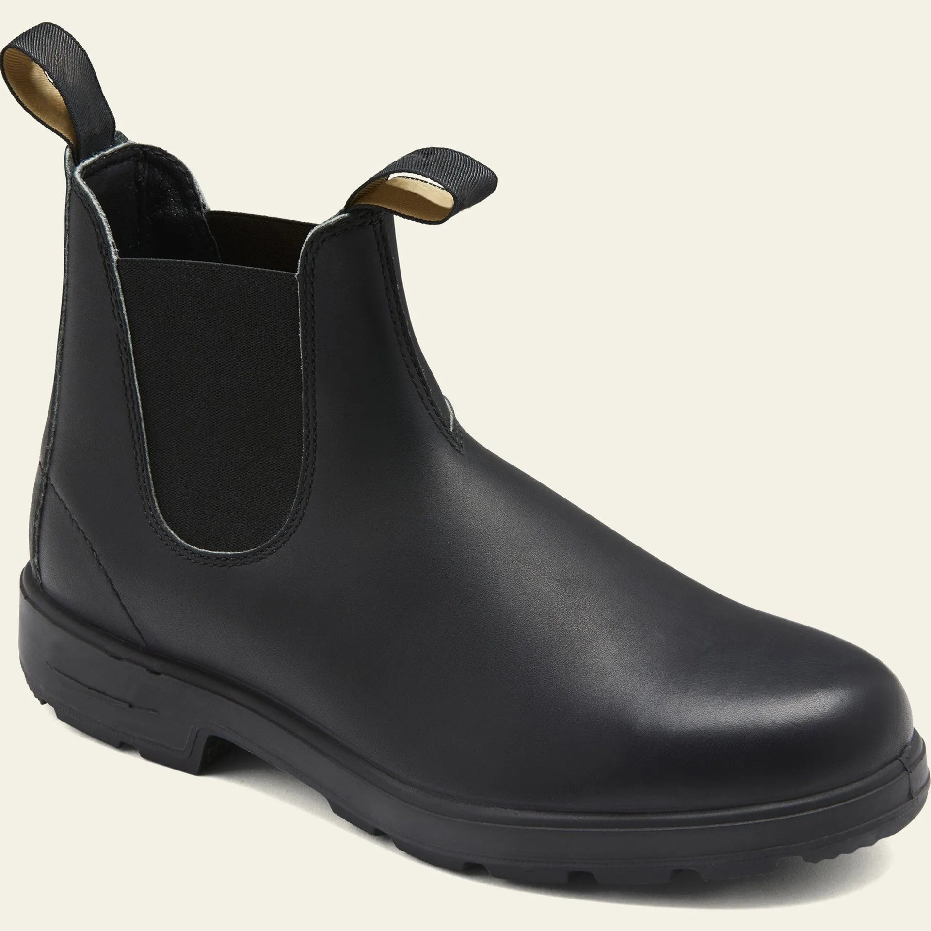 Vintage brown unisex Chelsea ankle boots with car suture stitching and a low heel on a wooden floor.