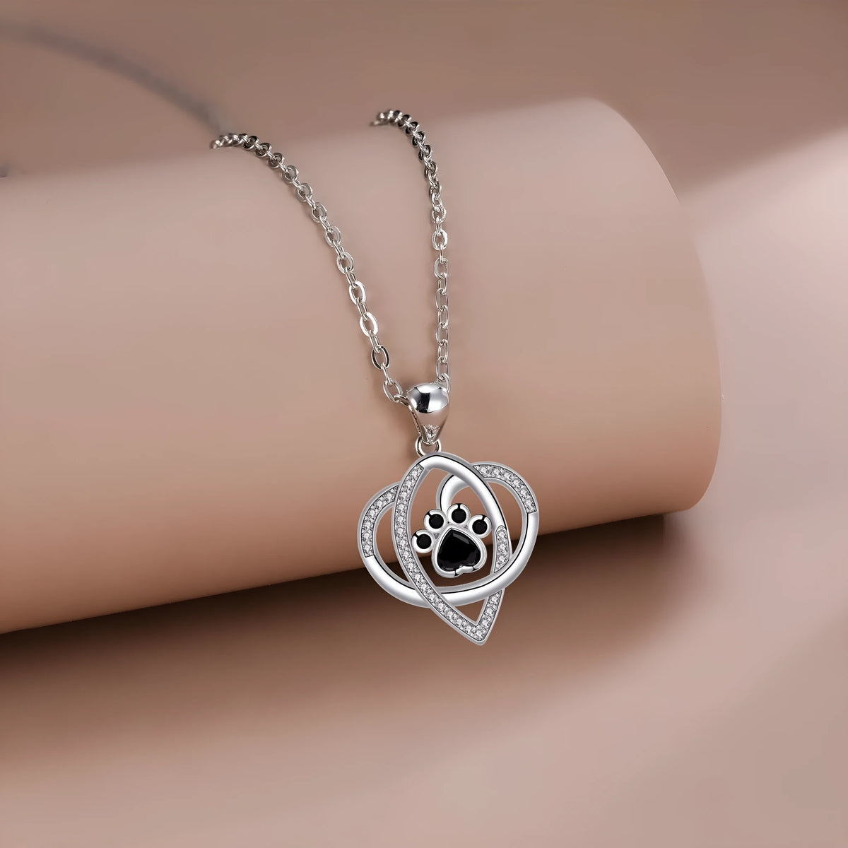 Close-up of a dog's paw print pendant necklace on a cross chain for women.